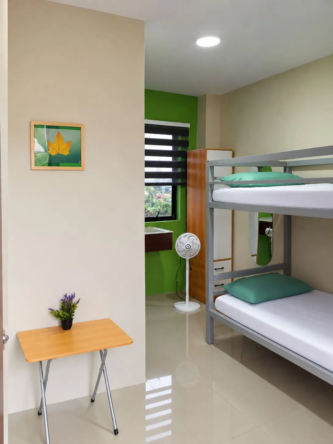 Rohan’s transient room in Alae with bunk beds, a table and standing fan
